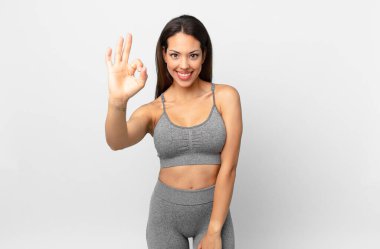 Genç İspanyol kadın kendini mutlu hissediyor, iyi bir jestle onaylıyor. fitness konsepti