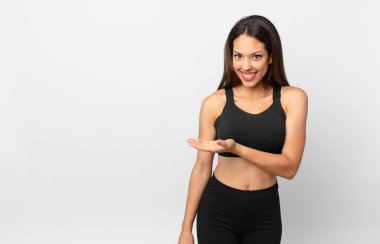 Genç İspanyol kadın neşeyle gülümsüyor, mutlu hissediyor ve bir konsept gösteriyor. fitness konsepti