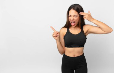Genç İspanyol kadın mutsuz ve stresli görünüyor, intihar jesti silah işareti yapıyor. fitness konsepti