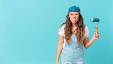 Genç ve güzel bir kadın, tiksinmiş ve rahatsız olmuş hissediyor. Dilini çıkarıp bir duvar boyuyor.