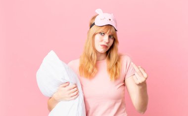 Güzel kızıl saçlı kadın kızgın, sinirli, asi ve agresif hissediyor. Pijama giyiyor ve yastık tutuyor.