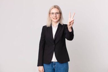 Gülümseyen ve mutlu görünen sarışın güzel kadın zafer ya da huzur işareti yapıyor. iş kavramı