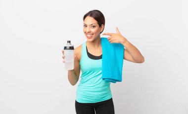 Genç İspanyol kadın kendine güvenerek gülümsüyor ve kendi gülüşünü gösteriyor. fitness konsepti