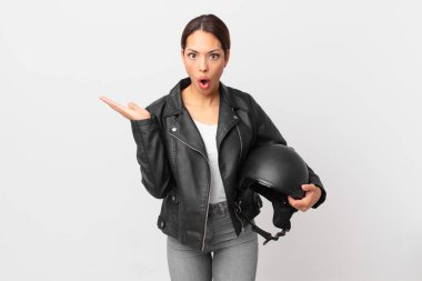 Genç İspanyol kadın şaşırmış ve şok olmuş görünüyor. Çenesi düşmüş ve elinde bir nesne tutuyor. Motosiklet sürücüsü konsepti