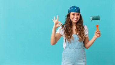 Genç, güzel bir kadın kendini mutlu hissediyor. Onayını veriyor. Güzel bir jest yapıyor ve duvar boyuyor.