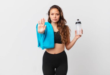 Genç ve güzel bir kadın ciddi görünüyor. Avuç içini gösteriyor. Durdurma hareketi yapıyor. fitness konsepti