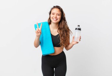 Genç, güzel bir bayan gülümsüyor ve iki numarayı gösteriyor. fitness konsepti