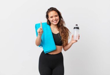 Genç, güzel bir bayan gülümsüyor ve arkadaş canlısı görünüyor. Bir numarayı gösteriyor. fitness konsepti