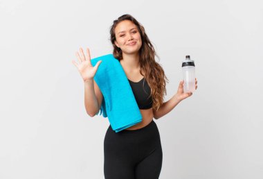 Genç, güzel bir bayan gülümsüyor ve arkadaş canlısı görünüyor, beş numarayı gösteriyor. fitness konsepti