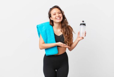 Genç, güzel bir kadın neşeyle gülümsüyor, mutlu hissediyor ve bir konsept gösteriyor. fitness konsepti