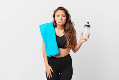 Genç, güzel bir kadın kafası karışmış ve şaşkın görünüyor. fitness konsepti