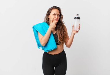 Genç, güzel bir kadın düşünüyor, kuşkulu ve şaşkın hissediyor. fitness konsepti