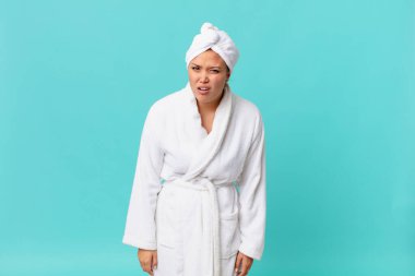 Genç güzel kadın şaşkın ve şaşkın hissediyor ve duştan sonra banyo cübbesi giyiyor.
