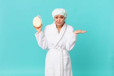 Genç, güzel bir kadın şaşkın, şaşkın, şüpheci ve duştan sonra bornoz giyiyor.