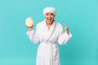 Genç, güzel bir kadın şoke olmuş, gülüyor, başarıyı kutluyor ve duş üstüne banyo bornozu giyiyor.