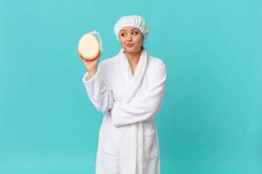 Genç, güzel bir kadın omuz silkiyor, kafası karışık ve kararsız ve duştan sonra banyo cübbesi giyiyor.