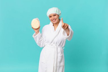 Genç, güzel bir kadın gülümsüyor ve arkadaş canlısı görünüyor. Bir numarayı gösteriyor ve duştan sonra banyo cübbesi giyiyor.