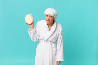 Genç güzel kadın şaşkın ve şaşkın hissediyor ve duştan sonra banyo cübbesi giyiyor.