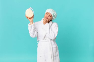 Genç ve güzel bir kadın duştan sonra banyo cübbesi giyer, kuşkulu ve şaşkın hisseder.