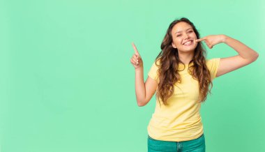 Genç ve güzel bir kadın kendi gülüşünü ve fotokopi alanını işaret ediyor.