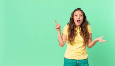 Genç ve güzel bir kadın şok olmuş ve şaşırmış hissediyor ve fotokopi alanını işaret ediyor.