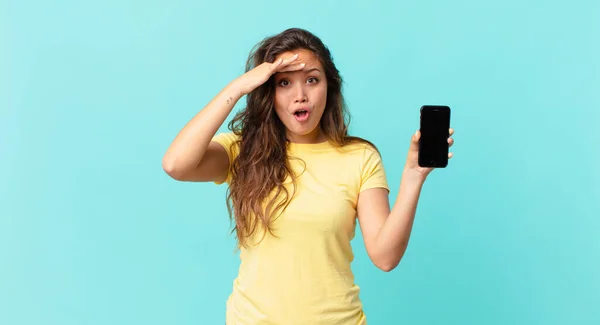 Joven Bonita Mujer Buscando Feliz Sorprendido Sorprendido Sosteniendo Teléfono Inteligente —  Fotos de Stock