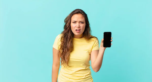 Młoda Ładna Kobieta Czuje Się Zakłopotana Zdezorientowana Trzyma Smartfon — Zdjęcie stockowe