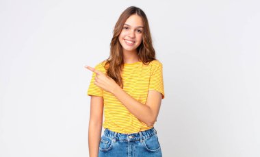 Genç, güzel bir kadın neşeyle gülümsüyor, mutlu hissediyor ve bir tarafı işaret ediyor.