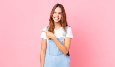 Genç, güzel bir kadın neşeyle gülümsüyor, mutlu hissediyor ve bir tarafı işaret ediyor.