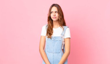 Genç, güzel bir kadın üzgün, üzgün ya da kızgın hissediyor ve yan tarafa bakıyor.