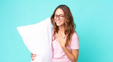 Genç ve güzel bir kadın pijama giyip elinde yastıkla çok komik bir şakaya gülüyor.