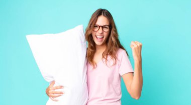 Genç ve güzel bir kadın sinirli bir ifadeyle bağırıyor pijama giyiyor ve yastık tutuyor.