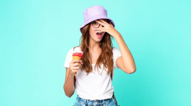 Genç, güzel bir kadın şok olmuş, korkmuş ya da korkmuş görünüyor. Elleri dondurma tutarken yüzünü kapatıyor. yaz konsepti