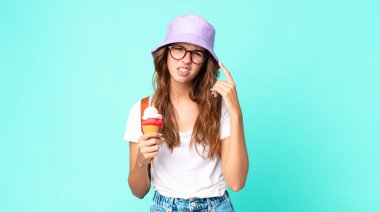 Genç ve güzel bir kadın kafası karışık ve şaşkın hissediyor. Dondurma tutarken kafayı yediğini gösteriyor. yaz konsepti