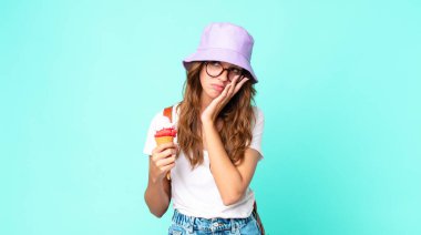 Genç ve güzel bir kadın, elinde dondurma tutan yorucu bir kadından sonra sıkılmış, hayal kırıklığına uğramış ve uykulu hissediyor. yaz konsepti