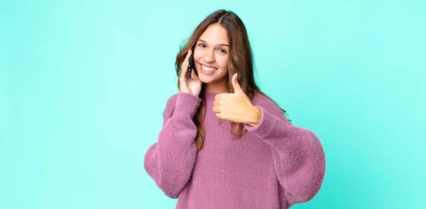 若い女性は誇りを感じ親指を上げて積極的に笑顔でスマートフォンを使い — ストック写真