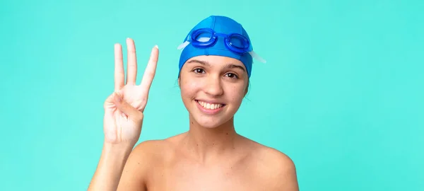 若い女性は笑顔で親しみやすく水泳ゴーグルで3番目を見せ — ストック写真