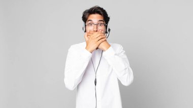 Genç İspanyol adam şok olmuş bir şekilde ağzını eliyle kapatıyor. tele pazarlamacı konsepti