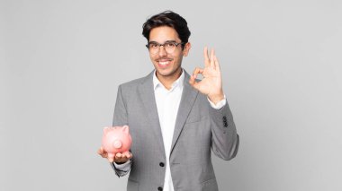 Genç İspanyol adam kendini mutlu hissediyor. Onaylıyor. İyi bir jestle ve elinde kumbarayla.