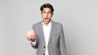 Genç İspanyol adam şok olmuş ya da şaşırmış görünüyor ve elinde domuz kumbarası var.