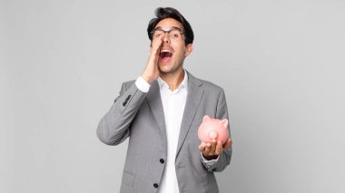 Genç İspanyol adam kendini mutlu hissediyor. Elleri ağızda, kumbarayı elinde tutarak bağırıyor.