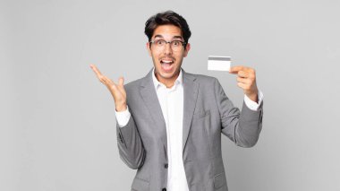 Genç İspanyol adam kendini mutlu ve şaşkın hissediyor. İnanılmaz bir şey ve elinde bir kredi kartı var.