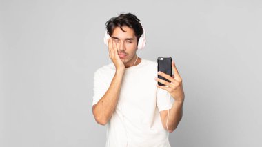 Genç İspanyol adam, kulaklıkları ve akıllı telefonlarıyla yorgun düştükten sonra sıkılmış, hayal kırıklığına uğramış ve uykulu hissediyor.