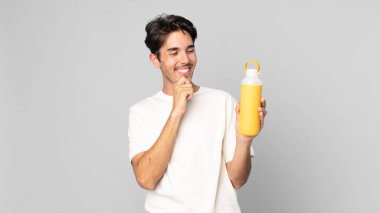 Mutlu, kendine güvenen, elleri çenesinde kahve termosuyla gülümseyen genç İspanyol bir adam.