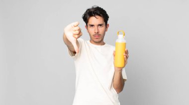 Genç İspanyol bir adam kızgın hissediyor, kahve termosuyla baş parmağını kaldırıyor.