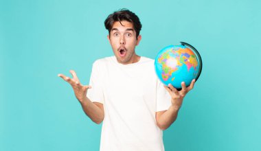 Genç İspanyol adam, inanılmaz bir sürprizle şaşkın, şaşkın ve şaşkın bir şekilde elinde bir dünya haritası tutuyordu.