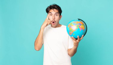 Genç İspanyol adam şaşırmış görünüyor, yeni bir düşünce, fikir ya da konsept buluyor ve elinde bir dünya haritası tutuyor.