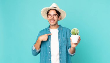 Genç İspanyol bir adam kendini mutlu hissediyor ve heyecanlı bir kaktüsle kendini işaret ediyor.