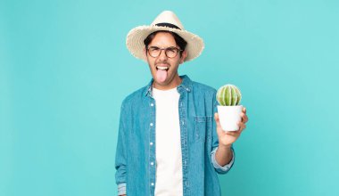 Neşeli ve asi tavırları olan genç İspanyol bir adam şaka yapıyor, dilini çıkarıp kaktüs tutuyor.