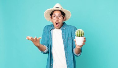 Genç İspanyol bir adam şok olmuş, şaşırmış ve elinde bir kaktüs tutuyor.